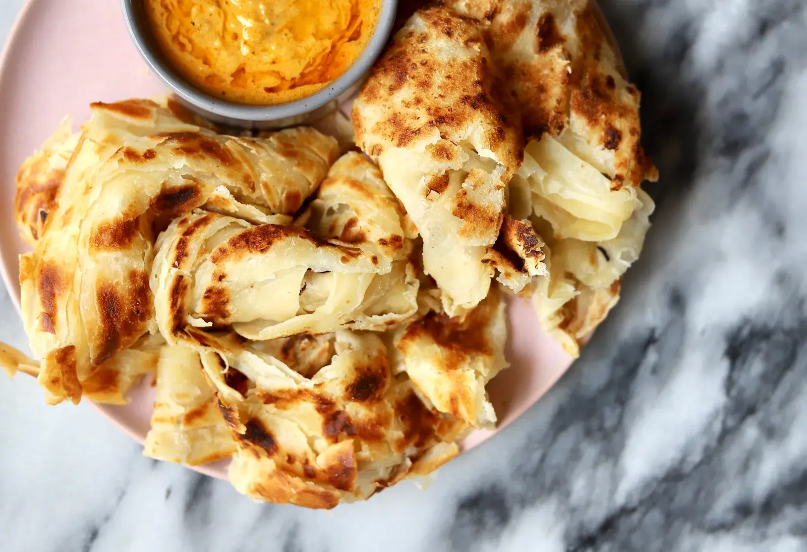 Crispy and soft Roti Canai flatbread served with curry dipping sauce