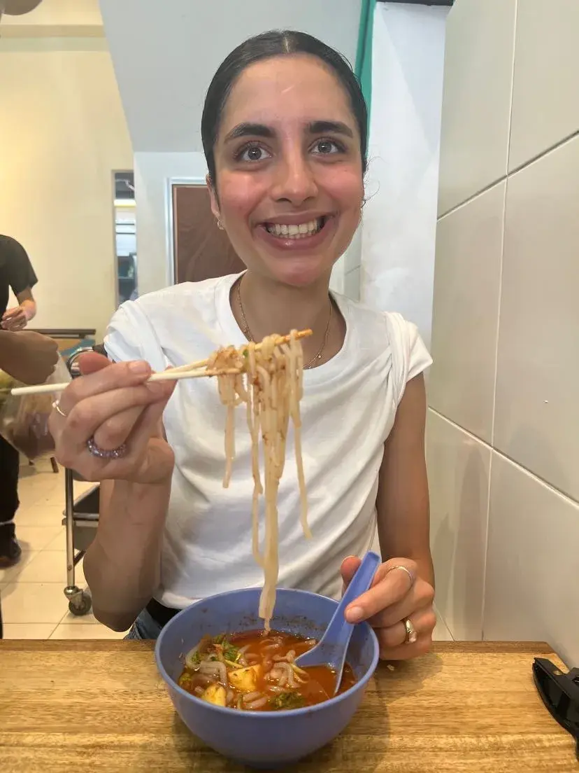 Deeva eating famous asam laksa at a restaurant in Penang, Malaysia